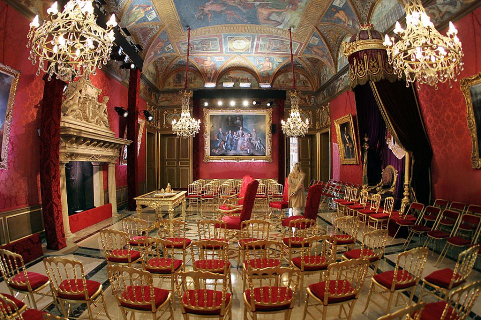 Impressive red and gold walls illuminated by crystal chandeliers and decorated with fine artwork in the Throne Room