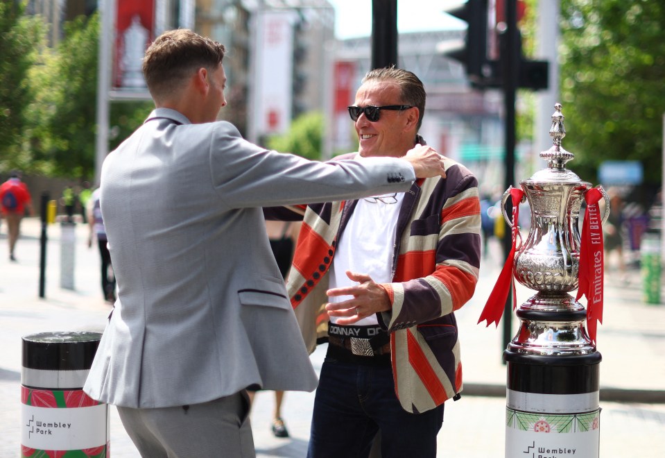 Fans are pictured with a FA Cup trophy replica outside the stadium