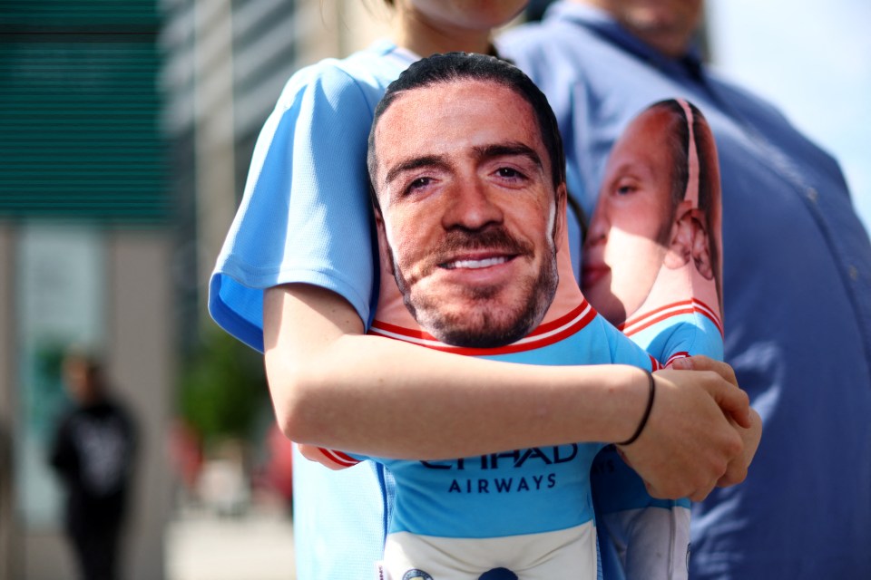 A young City fan carries a cushion bearing jack Grealish and Erling Haaland's faces