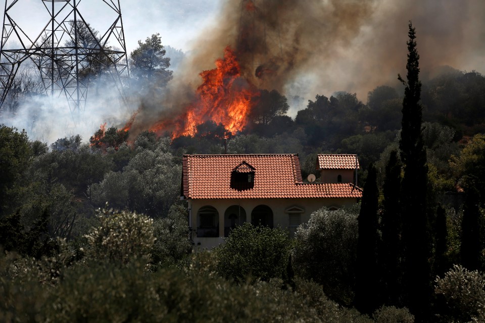 A raging fire burns next to electricity pylons in the Kouvaras area in Attica