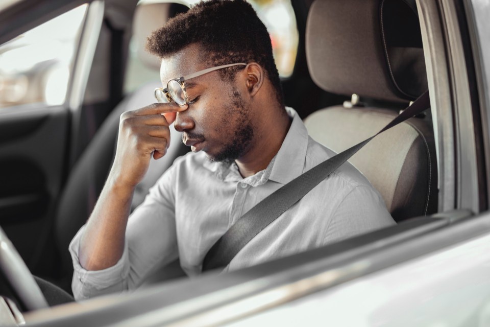 Stressed businessman feeling headache in car, stop the car, keeping hand to head and feeling anxiety