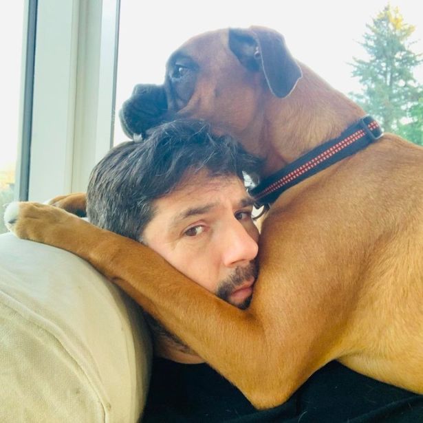 a man is laying on a couch with his head on a dog 's back