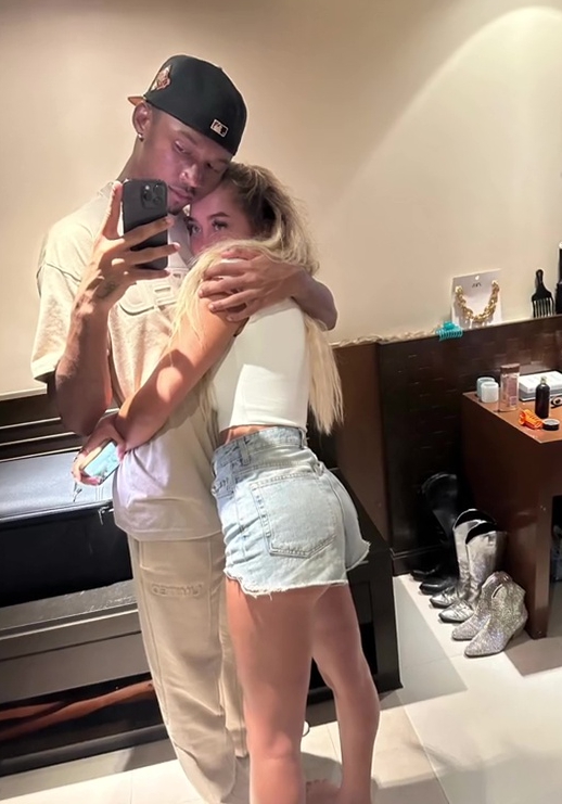 a man wearing a new york yankees hat kisses a woman on the cheek