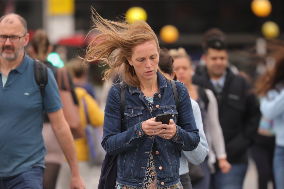 Commuters struggle during windy weather on Westminster Bridge, London, one Thursday morning