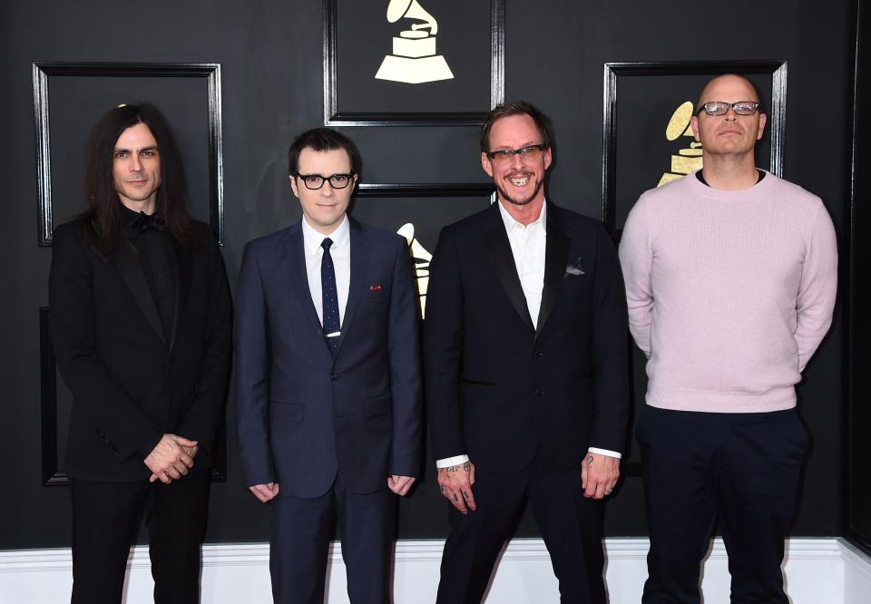 a group of men standing in front of a grammy plaque