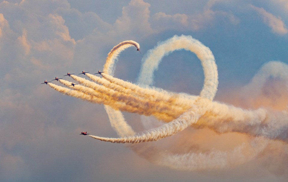 Six Red Arrows hold their formation as two others circle, creating a heart shape around them