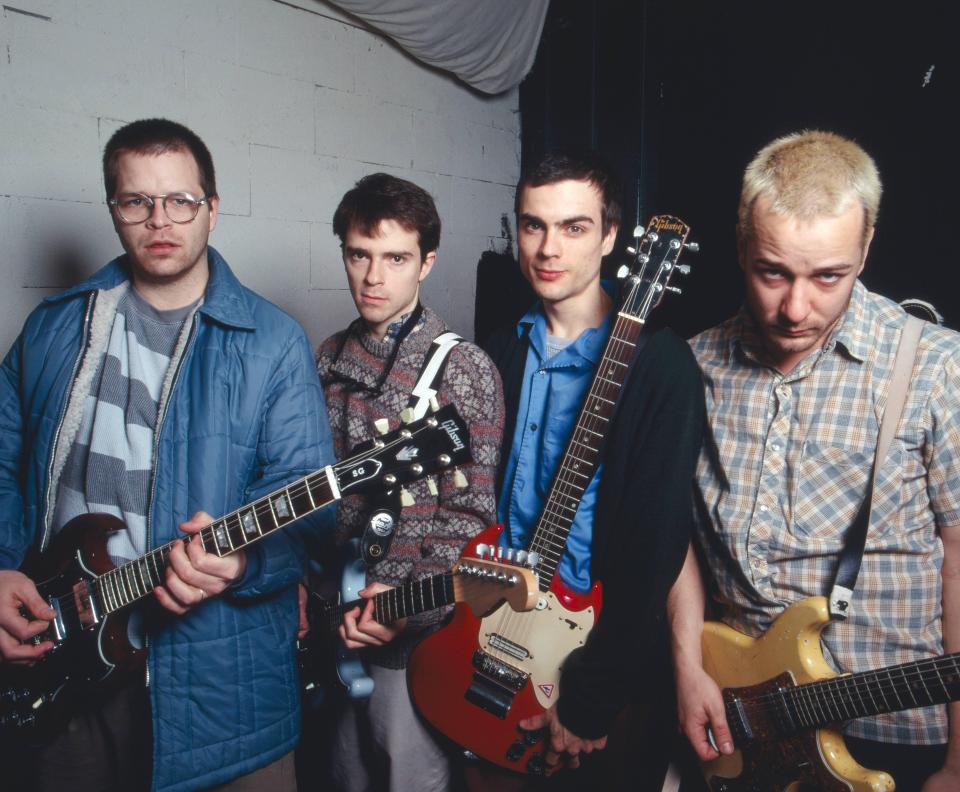 four men holding guitars one of which is a gibson