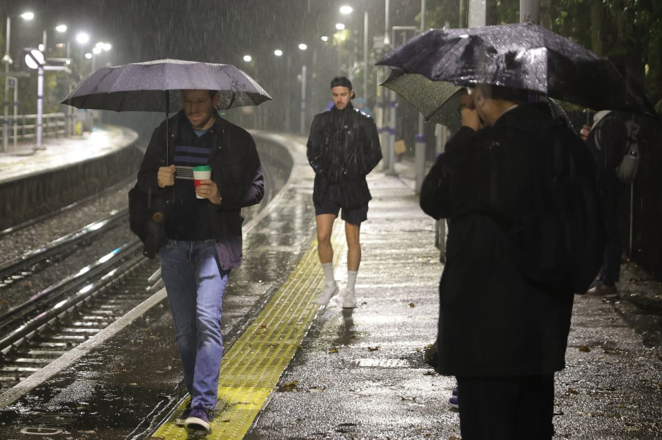 Commuters shelter during torrential rain at Maze Hill Station in Greenwich, South East London