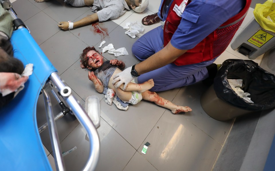 A young girl cries in agony as she lies on the hospital floor covered in blood