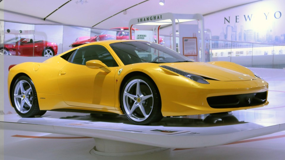 a yellow sports car is parked in front of a sign that says shanghai