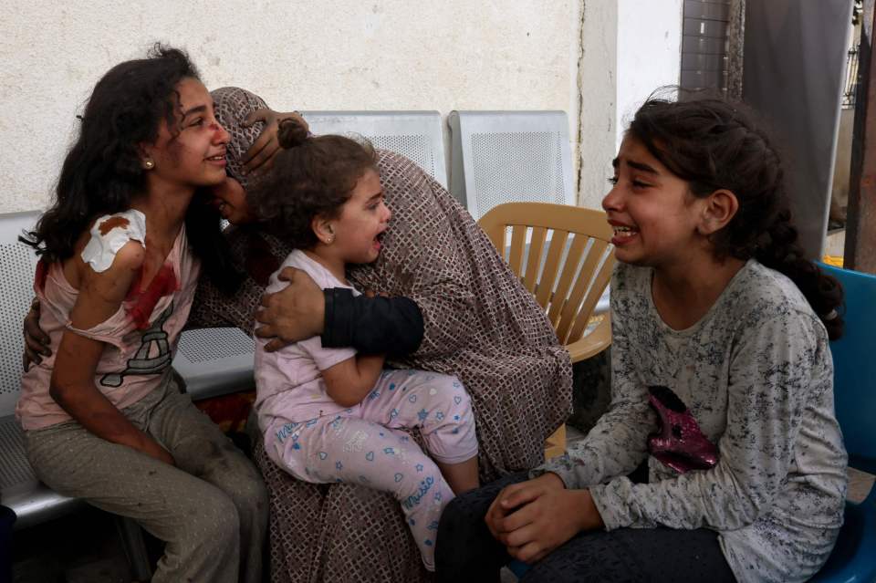 A woman comforts injured Palestinian girls waiting at the hospital to be checked