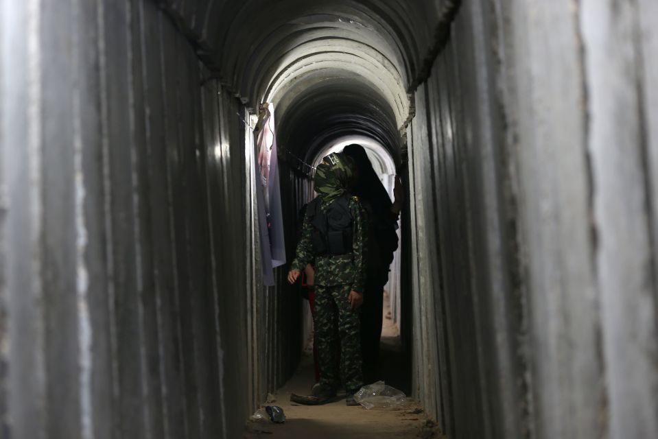 a man in a camouflage uniform stands in a dark tunnel