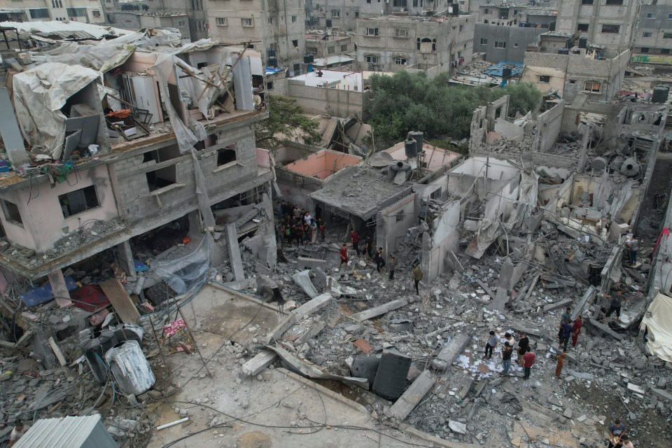 Palestinians walk through buildings destroyed in the Israeli bombardment on Sunday