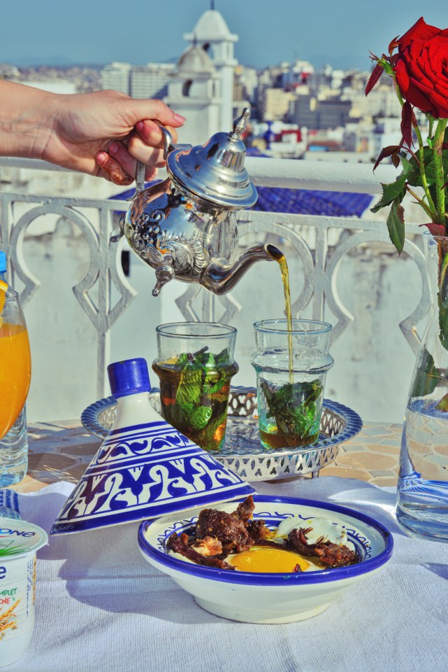 a woman holding in hand silver vintage teapot and pouring traditional mint sweet moroccan tea. Arabian hospitality and service.; Shutterstock ID 2023322096; purchase_order: -; job: -; client: -; other: -
