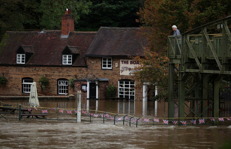 A woman looks out over the flooded beer garden of the Boat Inn after the River Severn burst its banks near Ironbridge