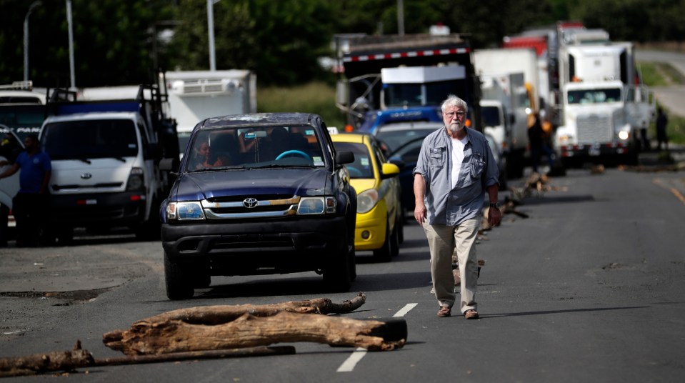 Chilling photos show the gunman walking through traffic before opening fire on protesters who were blocking the road