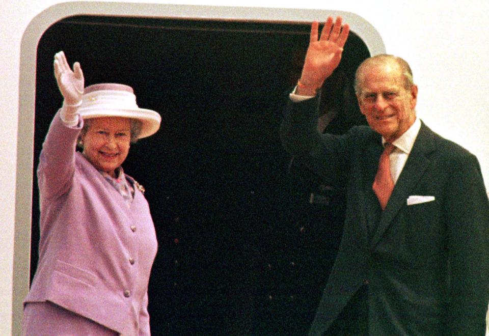 Queen Elizabeth II and Prince Philip waving goodbye at an airport.
