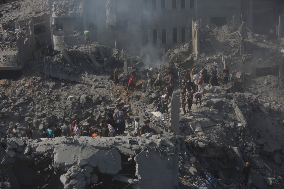 Palestinians look for survivors in the rubble of a destroyed building following an Israeli airstrike in the Bureij refugee camp