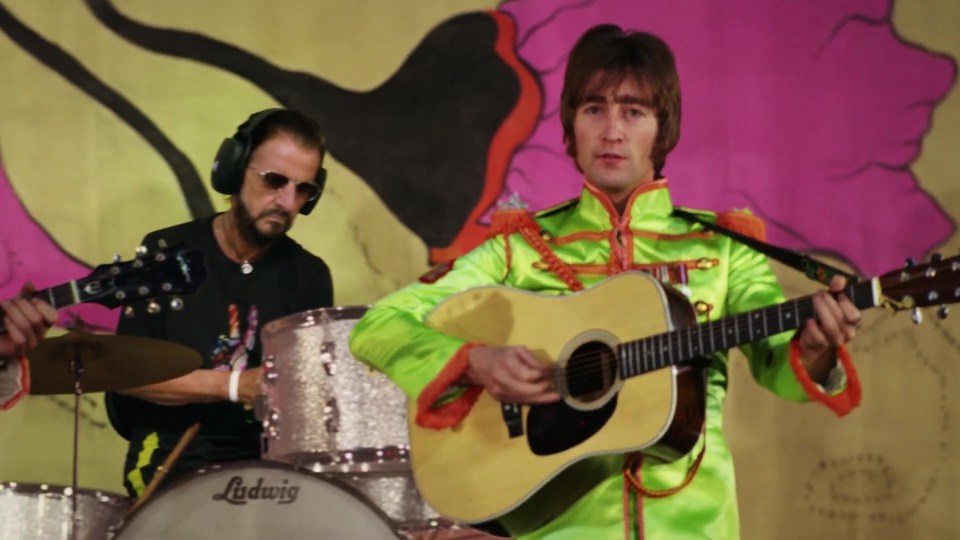 The video features Ringo Starr on the drums as digital John Lennon strums
