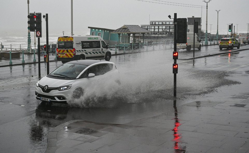 A car ploughs through puddles on the Brighton seafront on Saturday