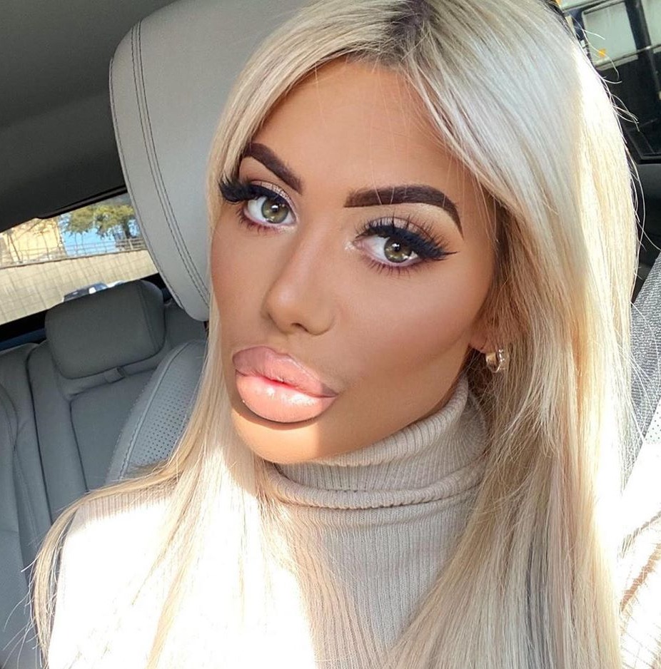 a woman with blonde hair and a turtleneck looks at the camera