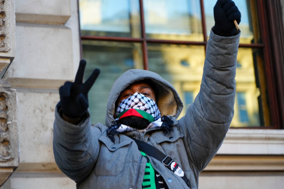 A masked demonstrator give s a V sign during a pro Palestinian march in London
