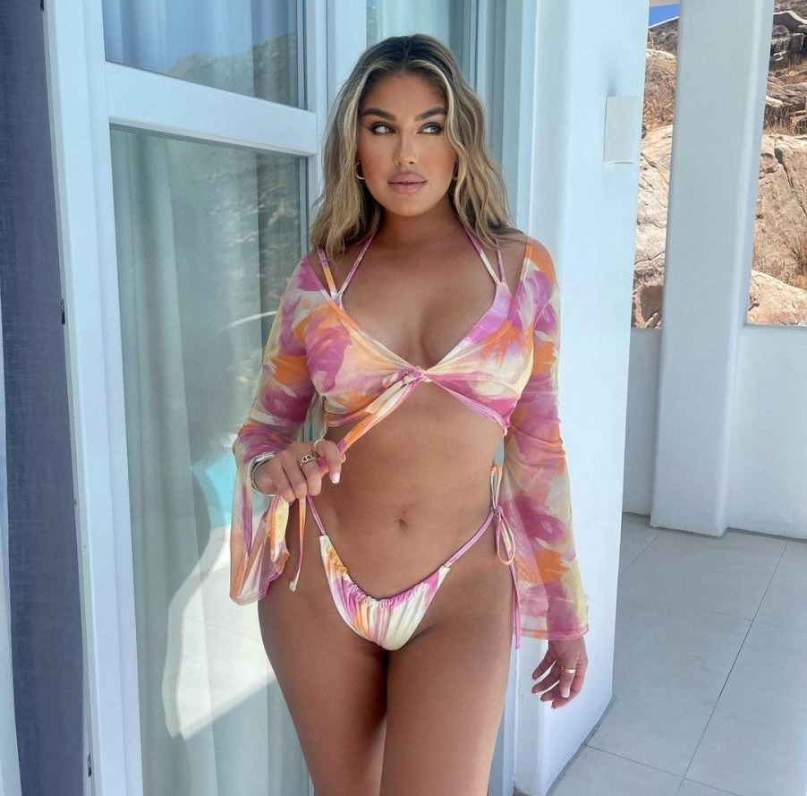 a woman in a bikini is standing in front of a window