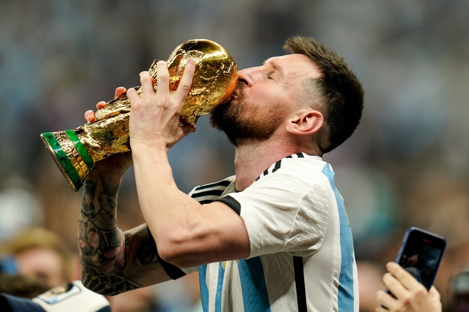 LUSAIL CITY, QATAR - DECEMBER 18: Lionel Messi of Argentina kisses the trophy after winning while sitting on the shoulders of a teammate after the FIFA World Cup Qatar 2022 Final match between Argentina and France at Lusail Stadium on December 18, 2022 in Lusail City, Qatar. (Photo by Tnani Badreddine/Defodi Images via Getty Images)
