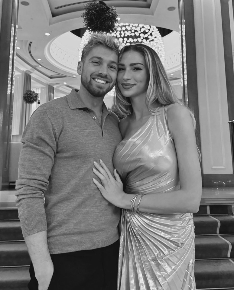 a man and woman are posing for a picture in front of a chandelier