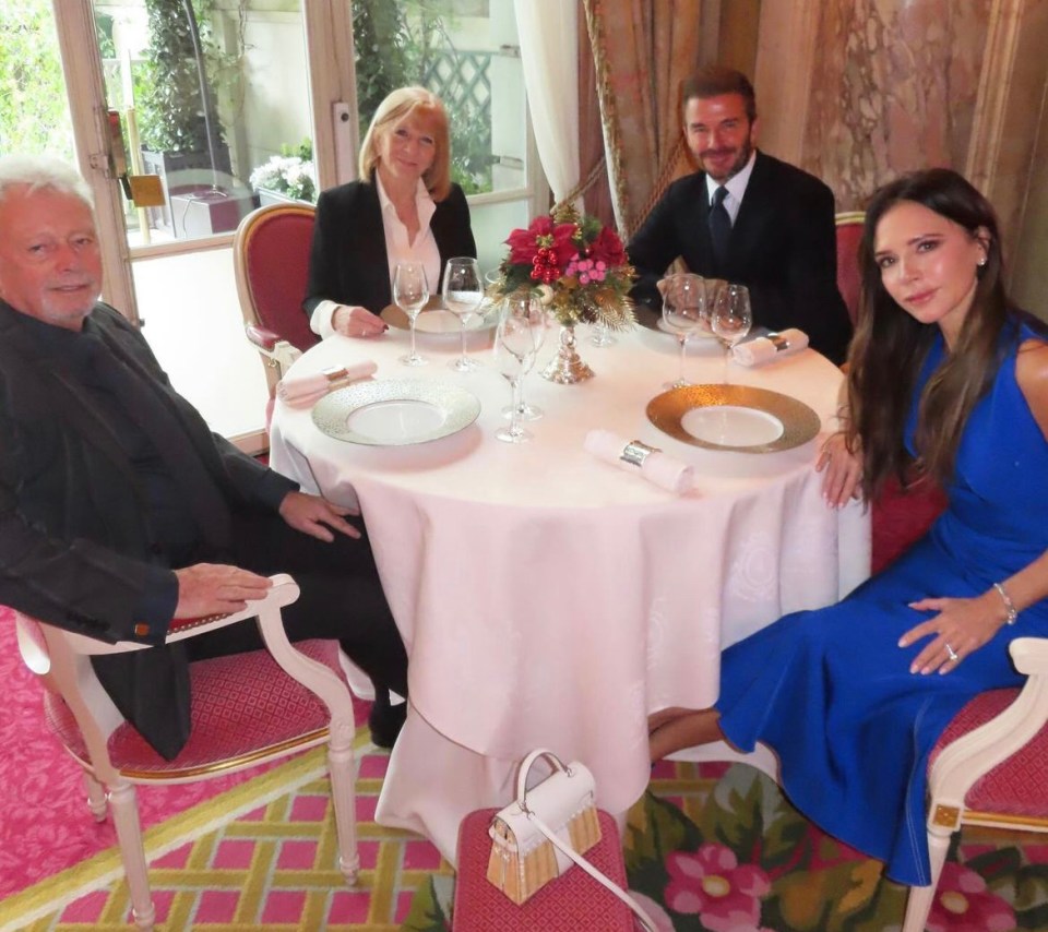 a woman in a blue dress sits at a table with three other people