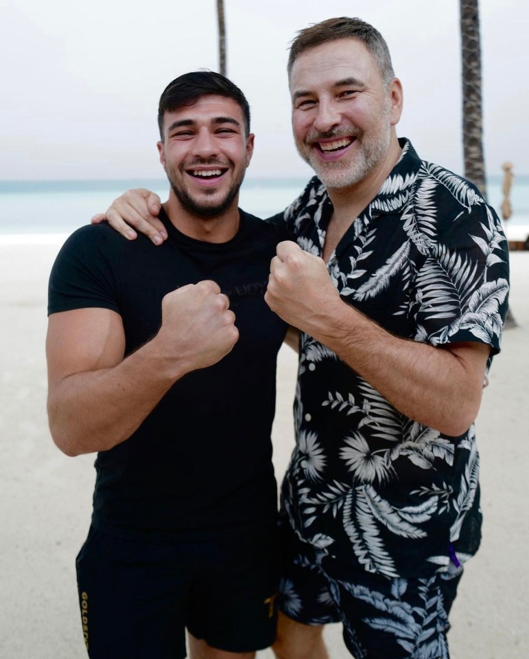 a man wearing a black shirt that says gold lion stands next to another man
