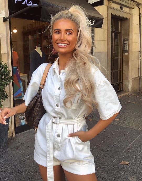 a woman wearing a white jumpsuit and shorts is smiling for the camera