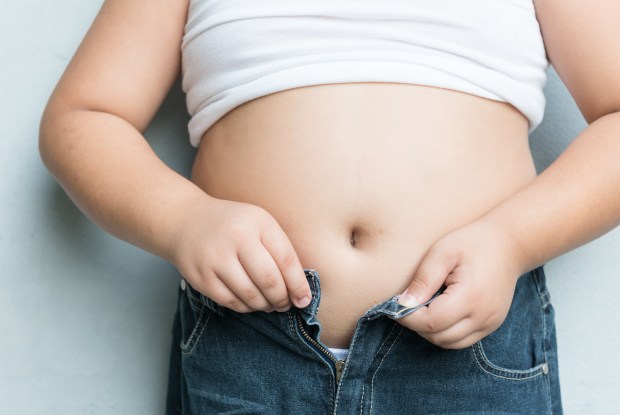 Overweight child struggling to fasten jeans.