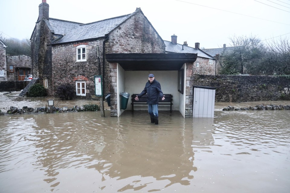 One man stands at a flooded bus stop in Croscombe, Somerset, on Sunday
