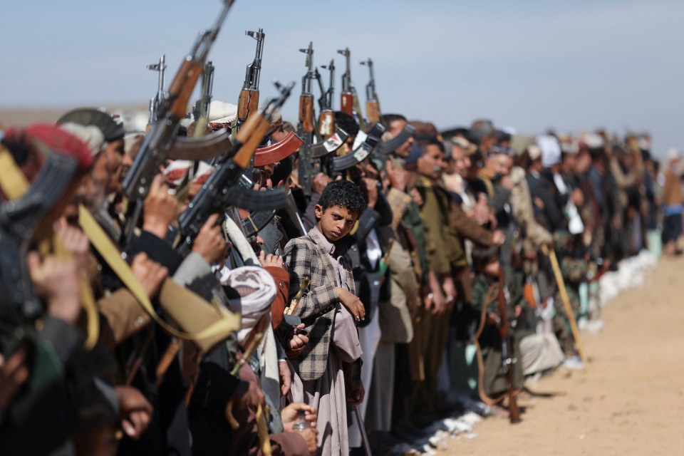 A boy looks on while attending a parade for new Houthi recruits