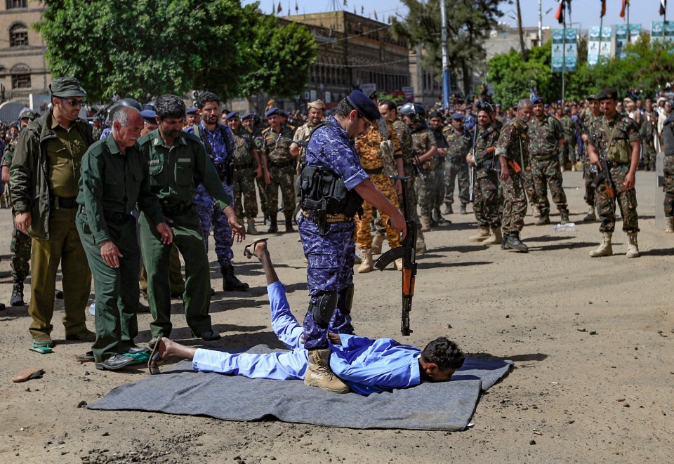 A member of the Yemeni security forces executes one of nine men convicted of being involved in the killing of a Houthi leader