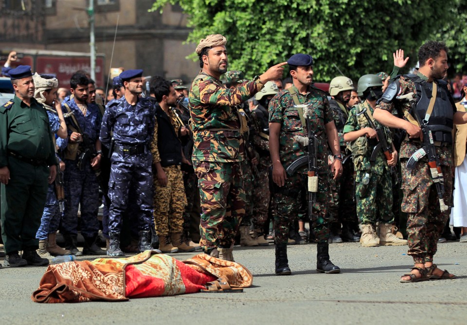 Yemeni security forces stand next to the body of a man who was executed after being convicted of killing his three daughters