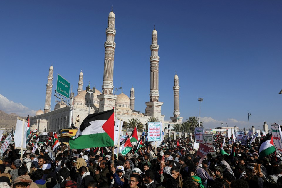 People demonstrate with placards showing the Houthi slogan