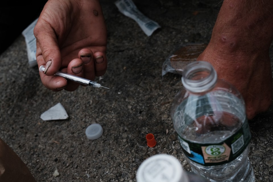 a person is holding a syringe next to a bottle of water
