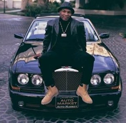 a man is sitting on the hood of a black car .