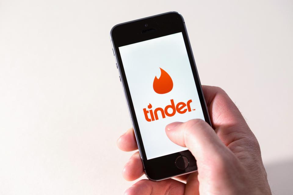 FXDM12 A man using the Tinder dating app on a mobile phone