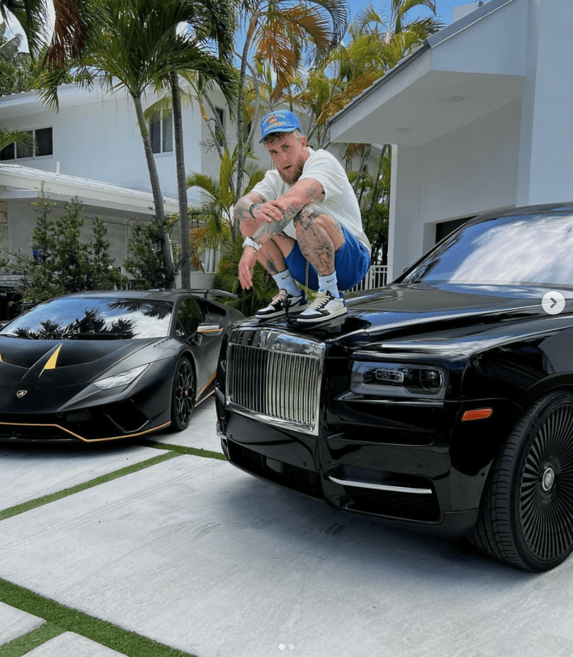 a man sits on the hood of a black rolls royce