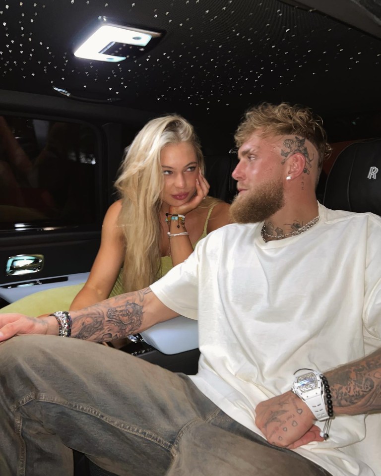 a man and a woman sit in the back seat of a rolls royce