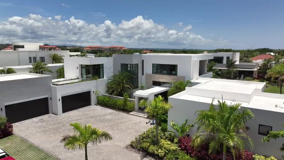 a row of white houses with black garage doors
