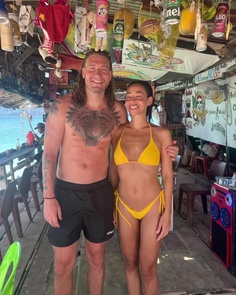 a man and a woman are posing for a picture in front of a sign that says ' coca cola ' on it