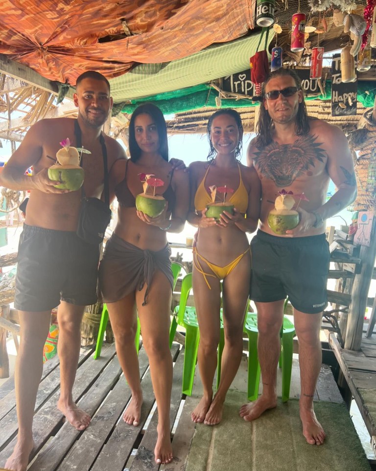 four people holding coconuts in front of a sign that says happy
