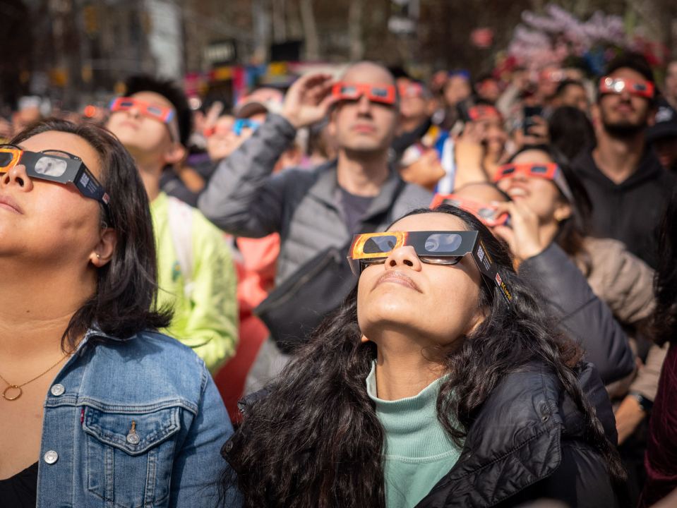 People wearing eclipse glasses watch a solar eclipse.