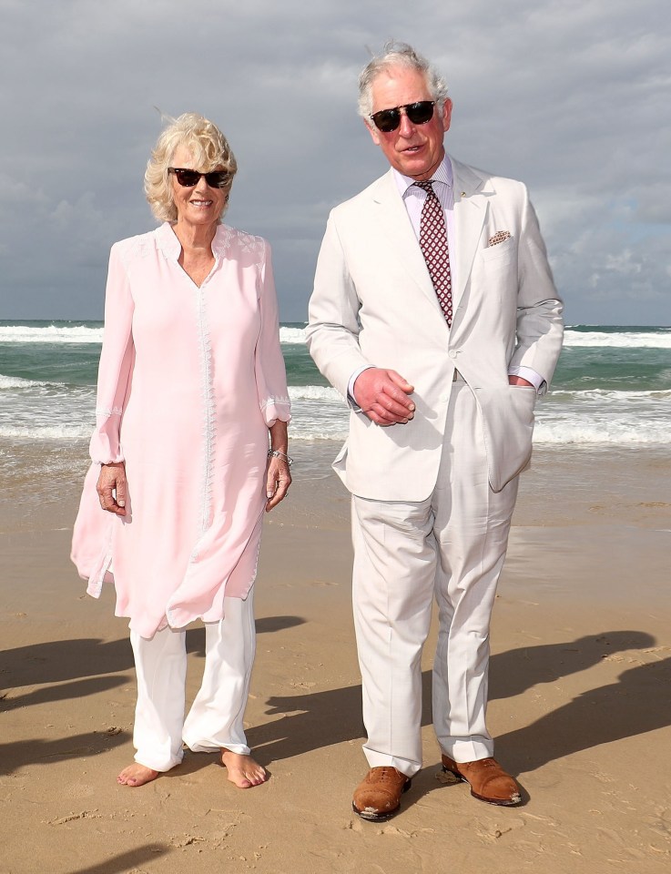 a man and a woman standing on a beach wearing sunglasses