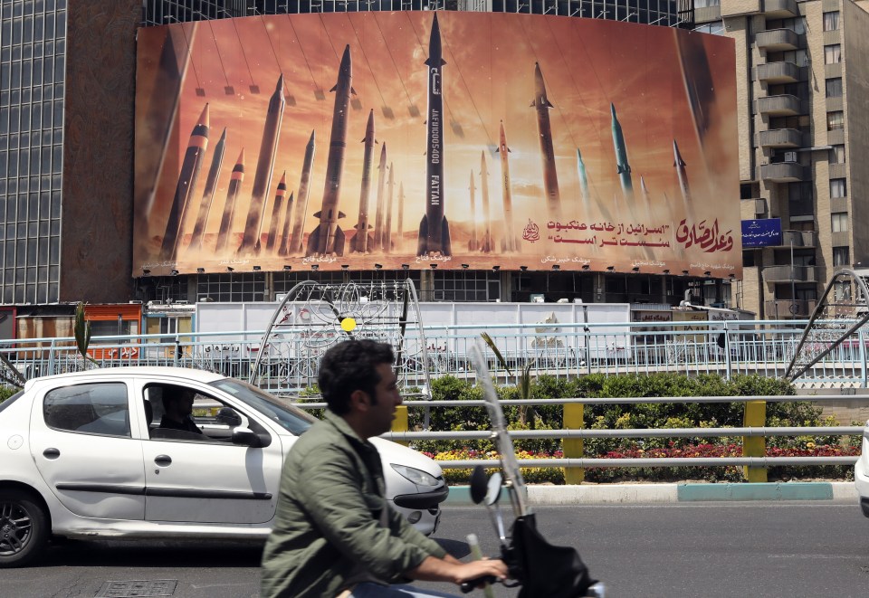 Iranians drive past an anti-Israel billboard carrying pictures of Iranian missiles in Tehran