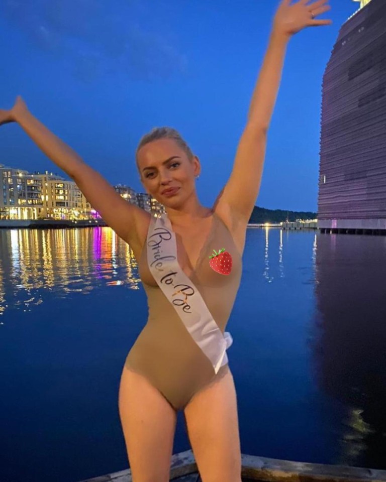 Woman in a nude swimsuit and "Bride to Be" sash, arms raised.